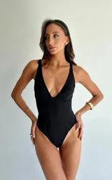 Body de color negro con escote en V profundo, diseño modelador con aros en el busto y corte de pierna alta.
