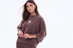 Buzo de felpa con friza, de corte holgado y diseño minimalista. Presenta cuello redondo, mangas cortas con terminación al corte y un pequeño parche rectangular en el pecho con la inscripción 'SELF LOVE CLUB'.