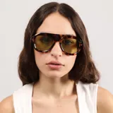 Lentes de sol con armazón de acetato negro y diseño de puente plano, estilo aviador moderno con cristales oscuros.