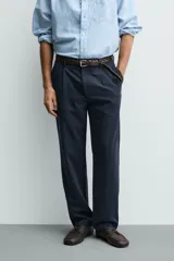 Pantalón de corte recto confeccionado en tejido elástico, con cintura elástica, pliegues frontales, bolsillos laterales y bolsillos traseros de vivo con botón.