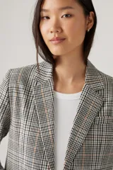 Blazer a cuadros color gris, con solapas de muesca, cierre frontal con un botón y bolsillos delanteros con solapa.