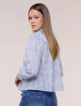 Blusa celeste de algodón con estampado floral, cuello mao fruncido con volado y cordel frontal con borlas. Tiene mangas largas abullonadas con puños elásticos y abotonadura frontal.