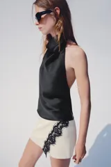 Falda pantalón cruzada de color crudo con detalle de encaje negro a contraste en el delantero y cierre posterior con cremallera oculta.