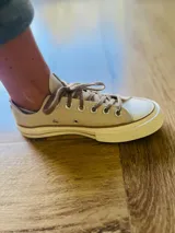 Zapatillas bajas de lona color blanco, con cordones marrones, puntera de goma y base blanca.