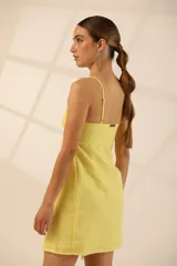 Vestido corto amarillo de lino, con breteles finos y corte cut-out en la cintura.