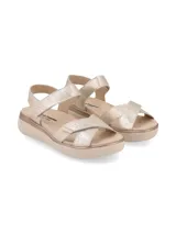 Sandalias de plataforma con tiras ajustables mediante velcro en el empeine y el talón. Presentan un acabado metalizado en tono dorado y una base de goma en color beige.