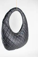 Cartera acolchada negra de silueta ovalada con asa circular integrada y diseño matelassé en rombos.