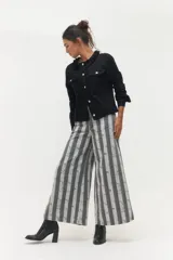 Pantalón de corte ancho y tiro alto con estampado de rayas verticales en tonos gris y blanco. Presenta cierre frontal con botón y bolsillos laterales.
