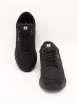 Zapatillas urbanas negras con suela gruesa y cordones.