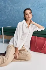 Camisa blanca de algodón, de calce relajado, con cuello camisero, frente abotonado y mangas largas abullonadas.