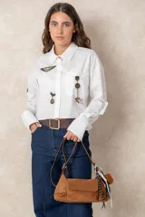 Cartera de gamuza color beige con correa ajustable de cuero sintético marrón, bolsillo frontal con solapa y cierre superior.