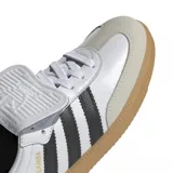 Championes adidas modelo Samba LT, de diseño clásico con base blanca, franjas laterales negras y suela de goma color caramelo. Presenta una lengüeta plegable característica y detalles en dorado.