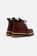 Borcego de cuero color marrón con diseño de costuras tipo mocasín en la puntera, cordones jaspeados y suela de goma con plataforma en capas.