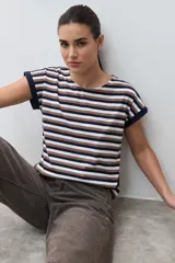 Remera de algodón con estampado de rayas horizontales en tonos azul marino, marrón y blanco. Presenta cuello redondo, mangas cortas con dobladillo y detalle de botones en el lateral inferior.