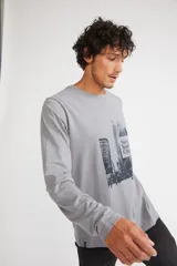 Remera de manga larga color gris melange, con cuello redondo y estampado gráfico en blanco y negro de la ciudad de Nueva York en el frente.