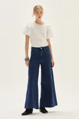 Jean de mezclilla azul oscuro, tiro alto, con pierna muy ancha (palazzo o wide leg) y costuras verticales marcadas en el frente.