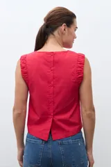 Blusa sin mangas color rojo, con cuello redondo y detalle de drapeado en los hombros. Presenta un corte recto y holgado.