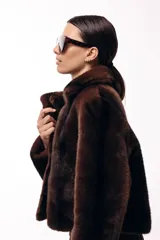 Tapado corto de piel sintética en color marrón chocolate, con cuello solapa amplio y cierre frontal oculto. Presenta una silueta estructurada y elegante.