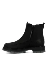 Botín tipo Chelsea de cuero negro con laterales elásticos, diseño de caña media y suela robusta de poliuretano con base gris traslúcida.