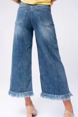 Pantalón de jeans azul de corte ancho con terminaciones desflecadas.