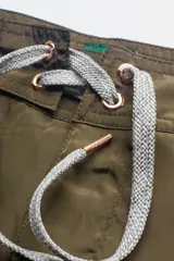 Short de baño verde oliva con cintura fija, bolsillo lateral con cierre y cordón circular bicolor.