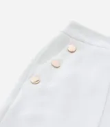 Bermuda de crepé color blanco, de corte holgado y tiro alto, con pliegues frontales y bolsillos laterales con detalle de botones. Confeccionada en poliéster y elastano.