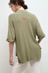 Camisa negra de tejido de punto acanalado, con cuello tipo polo y botones blancos.