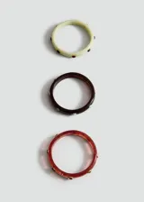 Set de tres pulseras rígidas de resina efecto carey en tonos verde claro, marrón oscuro y bordó, decoradas con apliques metálicos circulares con incrustaciones de piedras de colores.