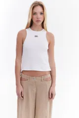 Top musculosa blanco de canalé con cuello redondo, corte ajustado y detalle de botones a presión en el lateral.