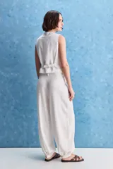 Pantalón negro de tiro alto y calce holgado, con pierna amplia, bolsillos laterales y puños ajustados con botones en los tobillos.