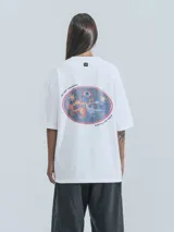 Remera blanca de corte holgado con estampa central en forma ovalada que incluye dragones, estrellas y un ojo, acompañada por el texto 'No Art Uruguay' y 'Castillo de Piria'.