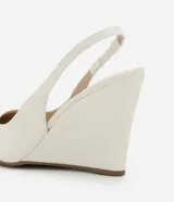 Zapato de tacón tipo anabela (cuña) color marrón oscuro, con punta fina y diseño slingback con tira elástica en el talón. Confeccionado en poliuretano con acabado liso.