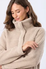 Campera de sherpa color beige, con cuello camisero, cierre frontal con botones a presión y detalles de ribete en la solapa y puños.