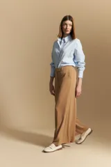 Pantalón ancho color tostado, de silueta fluida y cintura elastizada. Presenta una pretina ancha con botones metalizados irregulares.