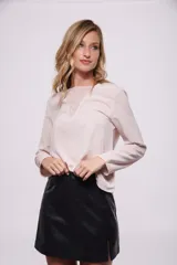 Blusa color rosa pálido con cuello redondo y mangas largas. Presenta detalle de lentejuelas en el escote.