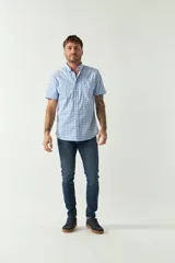 Camisa de manga corta con estampado de cuadros vichy en tonos celeste y blanco. Presenta cuello abotonado, cierre frontal con botones y logo bordado en el pecho.