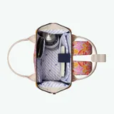 Mochila Cabaia Adventurer Pirae con estampado de hojas y flores en tonos rosa, naranja y amarillo sobre fondo blanco. Tiene sistema MOLLE, compartimento acolchado para tablet o PC, correa para sujetar a la maleta y tirantes acolchados antitranspirantes.