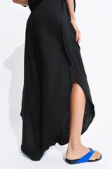 Pantalón de tiro medio confeccionado en lino, con cintura elástica ajustable mediante cordones. Presenta un diseño de pierna ancha con bajo redondeado y aberturas laterales.