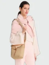 Cartera tipo bucket de tamaño pequeño, confeccionada en rafia natural con detalles en cuero color tostado. Presenta un cierre de cordón ajustable con el icónico detalle de bambú metálico de la línea Le Roseau y una correa larga ajustable para llevar al hombro o cruzada.