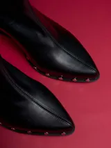 Botas negras de caña baja con punta fina y detalle de tachas plateadas en la suela.