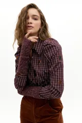 Camisa de manga larga con estampado de cuadros y bordados florales pequeños. Presenta cuello camisero clásico, cierre frontal con botones de nácar y hombros abullonados con frunces.