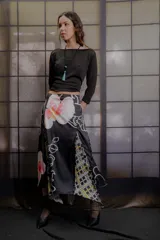 Falda midi de tiro medio confeccionada en tela sedosa color azul marino, con aberturas frontales y traseras que aportan movimiento, y estampado floral en la parte inferior.