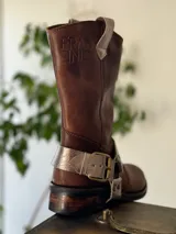 Bota de cuero marrón con estribo desmontable plateado.