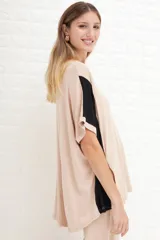 Remerón de manga corta, color beige claro, con bloques de color negro en las mangas. Presenta cuello redondo y un calce holgado.