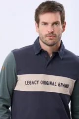 Remera tipo polo de manga larga con diseño color block en azul marino, verde y una franja central en beige con el texto Legacy Original Brand estampado. Presenta cuello camisero con cierre de botones y puños acanalados.