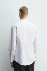Camisa slim fit de algodón en color blanco, con cuello smoking y manga larga con puño doble abotonado.