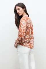 Camisa de manga larga con estampado floral en tonos ladrillo y blanco, con cuello camisero y cierre frontal de botones.