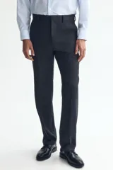 Pantalón de traje negro, de corte regular fit y silueta clásica, con bolsillos laterales y traseros ribeteados, cierre con cremallera y botón oculto.