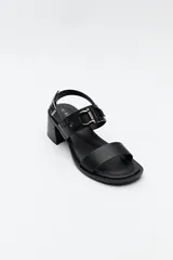 Sandalias de cuero color marrón con tacón cuadrado y hebilla lateral.