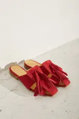 Zueco plano de cuero color dorado, con diseño de tiras anchas entrelazadas en el empeine y punta cuadrada.